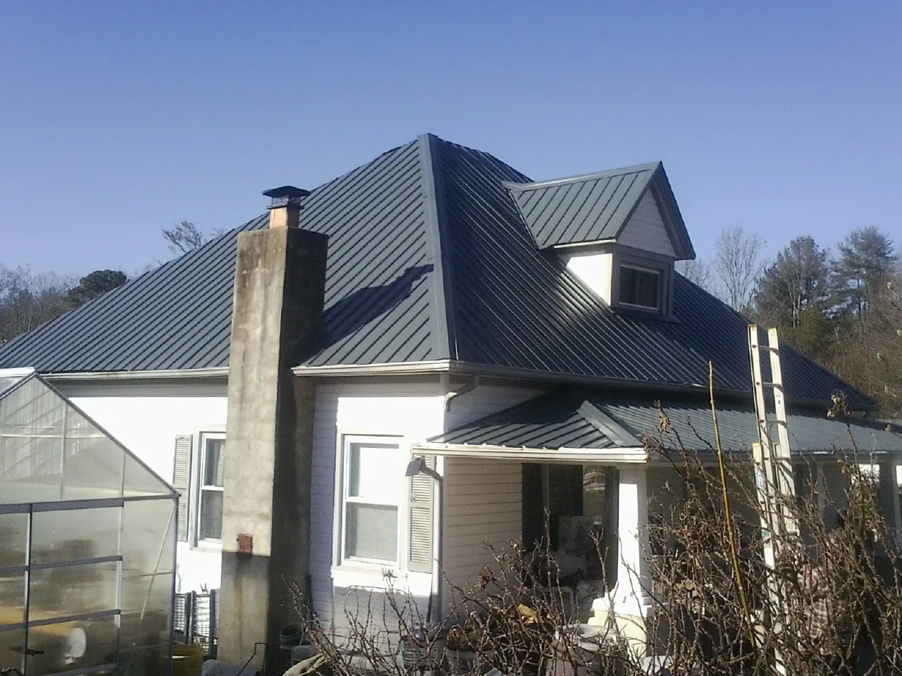Dark blue standing seam metal roof on a white farmhouse with dormer — Slate & Tile Roof Repair by Roofing Brothers in Roebling