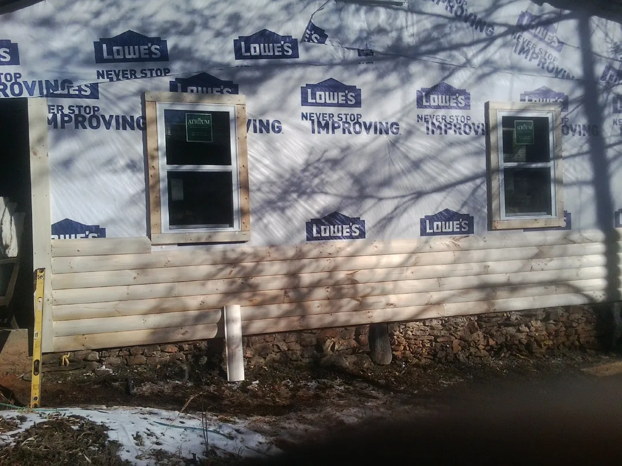 House wrap and new log siding going up on an exterior wall in Roebling