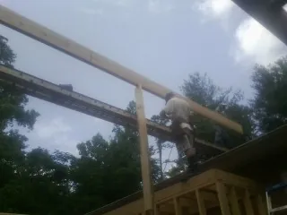Carpenter setting a ridge beam over a new addition frame — Ice Dam Removal by Roofing Brothers in Roebling