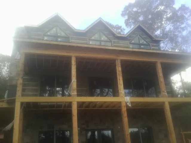 Dormers and porch framing on a large log home under construction — Roof Coating work by our crew in Roebling