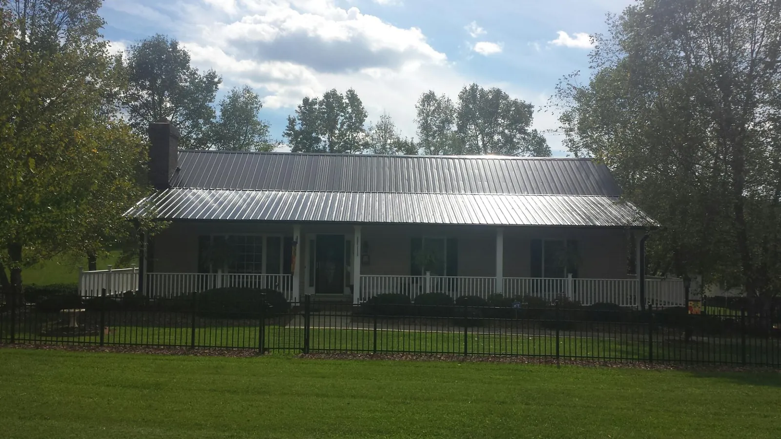 Gray metal roof on a brick ranch with a full width front porch — Gutter Guard Installation work by our crew in Roebling