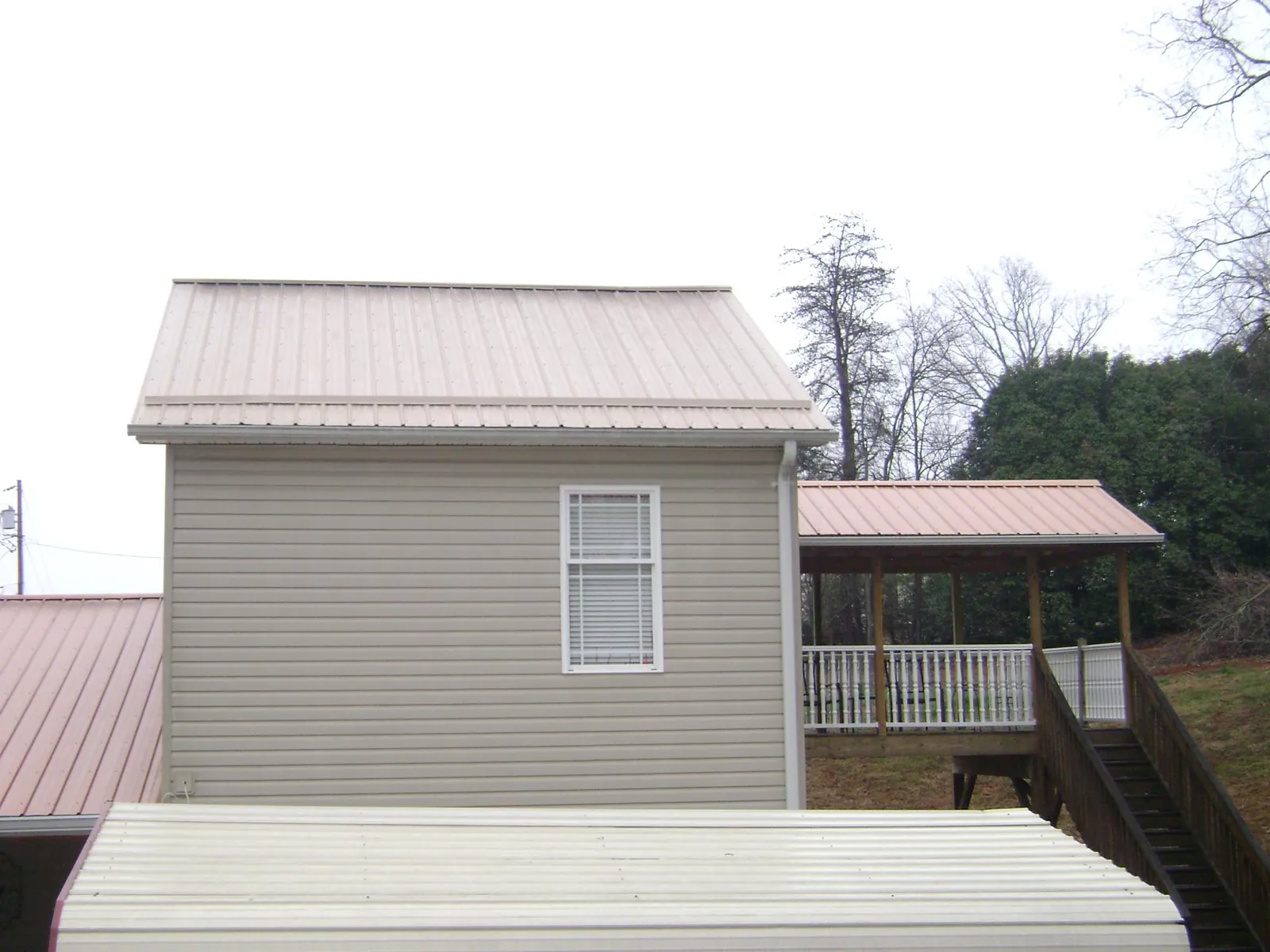 Tan metal roofs on a two story addition and attached porch, from a Roof Replacement job in Roebling