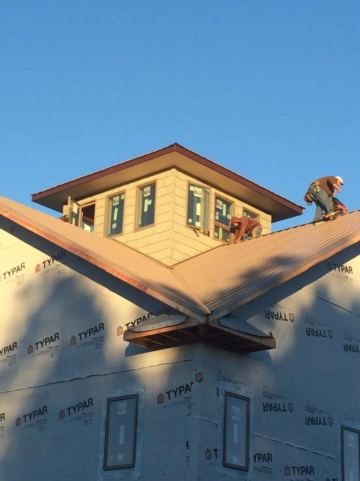 Roofers working around a rooftop cupola on a new metal roof at sunset — Roof Waterproofing in Roebling by Roofing Brothers